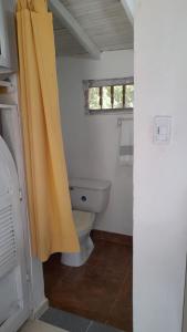 a bathroom with a toilet and a yellow shower curtain at Casa Horizontes in San Carlos