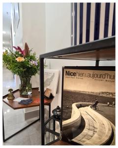 una mesa con un jarrón de flores y una señal en Le Petit Trianon et le Charme des Suites, en Niza