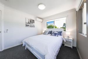 a white bedroom with a bed and a window at Calamvale Business or Holiday like Home in Brisbane