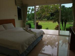a bedroom with a bed and a large window at Vimannam Resort in Phetchaburi