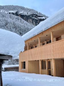 ein schneebedecktes Gebäude mit Bergen im Hintergrund in der Unterkunft Wasserfall Apartments Mellau in Mellau