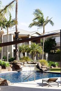 - une piscine avec un banc et des palmiers dans l'établissement Mulwala Lakeside Apartment, à Mulwala