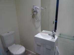 a bathroom with a toilet and a sink and a phone at Sahara Deluxe Studios in Dunedin