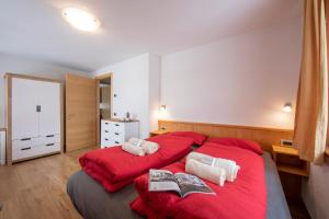 a bedroom with two beds with red sheets and towels at Fiocco Di Neve Ski in- Ski out Mt 10- Happy Rentals in Livigno