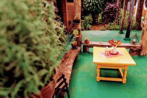 a table and benches in a garden with a plant at Pousada Chácara Rama in Botucatu