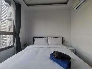 een slaapkamer met een wit bed met een blauwe handdoek erop bij Super 1BDR in Water Park Resort in Pattaya South