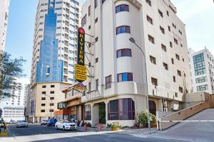OYO 118 Revira Hotel في المنامة: مبنى على شارع فيه سيارات تقف امامه