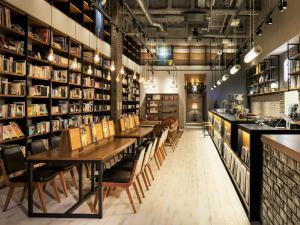 a restaurant with tables and chairs in a room with bookshelves at LAMP LIGHT BOOKS HOTEL fukuoka in Fukuoka