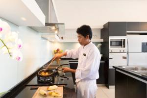 a man cooking food in a kitchen at Villa Kavya - 8-minute walk from Berawa Beach in Canggu