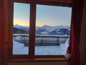 una ventana con vistas a las montañas cubiertas de nieve en Studiò Pila 1800, en Pila