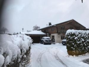 ein schneebedecktes Haus mit einem Auto in der Einfahrt in der Unterkunft Egger Studio Hornblick in Reith bei Kitzbühel