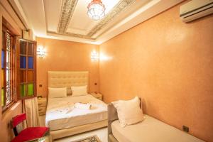een kleine kamer met 2 bedden en een bank bij Riad Aymane in Marrakesh