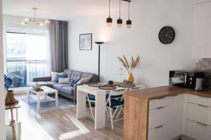 eine Küche und ein Wohnzimmer mit einem Tisch und einem Sofa in der Unterkunft Apartament HAMPTONS Gdynia in Gdynia
