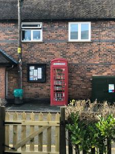 an old red phone booth in front of a brick building at Moss Cottage in Willaston