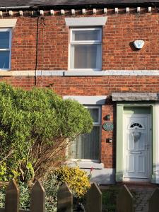 a brick house with a white door and a window at Moss Cottage in Willaston