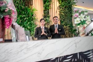 two men in suits standing in front of a counter at Luminor Hotel Jember By WH in Jember