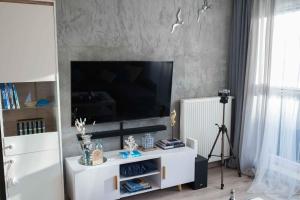 Apartament HAMPTONS Gdynia في غدينيا: غرفة معيشة مع تلفزيون بشاشة مسطحة على جدار