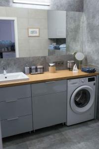 uma cozinha com uma máquina de lavar roupa e um lavatório em Apartament HAMPTONS Gdynia em Gdynia