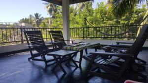 drie stoelen en een tafel op een veranda met een hangmat bij COCO house in Galle