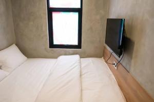 a small room with two beds and a tv at M Cabin Karawaci in Binong