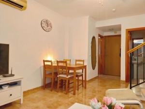 salon ze stołem i krzesłami oraz zegarem na ścianie w obiekcie Nerja Sun Apartments Casa Cipreses 9 w mieście Nerja
