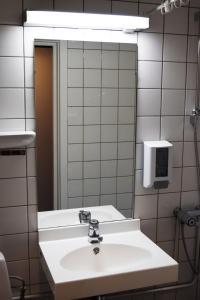Rjukan hotell في Rjukan: حمام مع حوض أبيض ومرآة