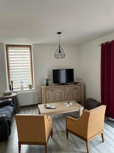 a living room with a tv and a table and chairs at Le Gîte de la Vilaine in Sainte-Anne-sur-Vilaine