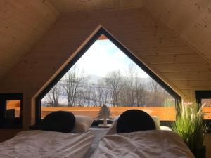 two people laying on beds in a room with a window at Chatki wisla houses in Wisła