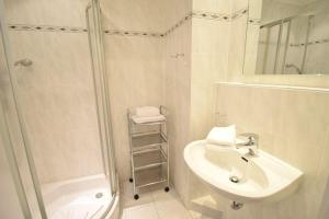 een witte badkamer met een douche en een wastafel bij App-Stadtoase-Haus-Nordland in Westerland