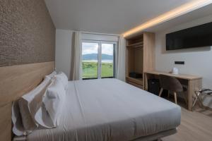 a bedroom with a bed and a desk and a window at Hotel Spa Meiga do Mar in Caldebarcos