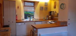 a kitchen with yellow walls and white cabinets and a sink at Andreu Cottage in Callander