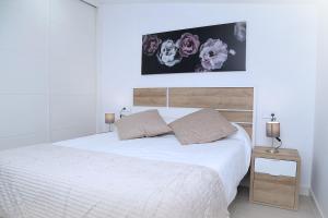 een witte slaapkamer met een wit bed met 2 kussens bij Ático Plaza Mercado 4,5 in Salamanca