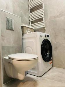 a bathroom with a toilet and a washing machine at Apartament Przytulny in Kołobrzeg