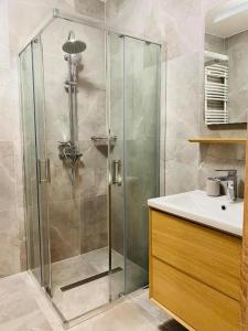a bathroom with a glass shower and a sink at Apartament Przytulny in Kołobrzeg