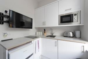 uma cozinha com armários brancos e um micro-ondas em Fabulous Apartment in Superb location em Londres