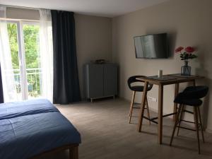 a bedroom with a bed and a table and a television at 2nd Home Appartements 23 in Nieder-Olm