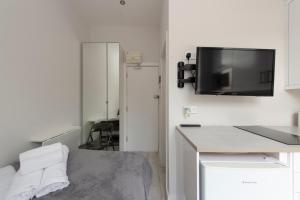 Kleines weißes Zimmer mit einem TV an der Wand in der Unterkunft Fabulous Apartment in Superb location in London