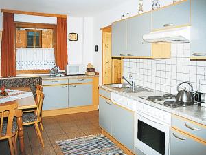 a kitchen with blue cabinets and a table and a kitchen with a stove at Holiday Home Reinbacher - GBM100 by Interhome in Gröbming