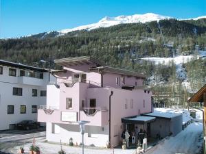 um edifício cor-de-rosa com uma montanha coberta de neve ao fundo em Apartment Rubin - SOE265 by Interhome em Sölden