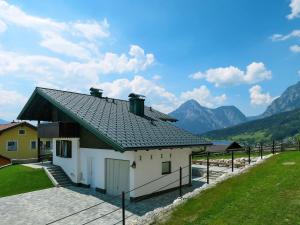 a house with a roof with mountains in the background at Holiday Home Jung - GBM240 by Interhome in Gröbming