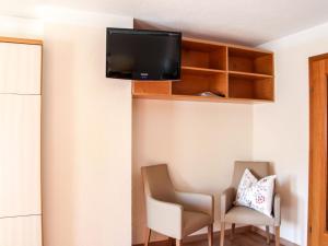 プルツにあるApartment Apart Grazia - PTZ152 by Interhomeの壁にテレビと椅子2脚が備わる客室です。