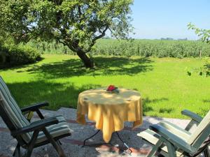 a table with a yellow table cloth and two chairs at Apartment Landhaus Mahnhamm-2 by Interhome in Wiarden