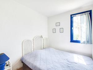 a white bedroom with a bed and a window at Apartment Les terrasses de la Plage-1 by Interhome in Cap d'Agde