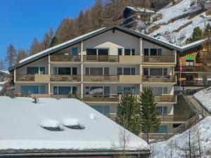 un grand immeuble avec de la neige au sol dans l'établissement Apartment Kondor by Interhome, à Zermatt
