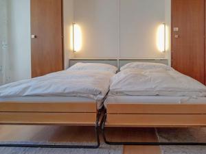 Una cama con sábanas blancas y almohadas. en Apartment Kondor by Interhome, en Zermatt