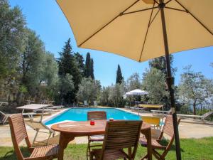 einen Tisch und Stühle mit einem Sonnenschirm vor dem Pool in der Unterkunft Holiday Home Podere Le Coste by Interhome in Paterna