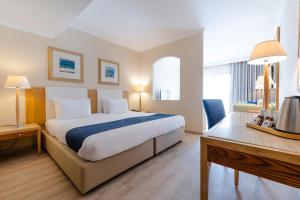 a hotel room with a bed and a desk at Maritim Antonine Hotel & Spa in Mellieħa
