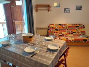 a table with plates and dishes on it with a couch at Apartment Pierres Blanches F et H by Interhome in Le Cugnon