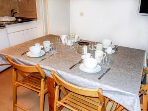 una mesa con tazas y platillos. en Apartment Pierres Blanches F et H by Interhome en Le Cugnon