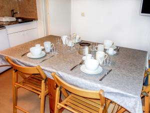 a table with cups and saucers on it at Apartment Pierres Blanches F et H by Interhome in Le Cugnon